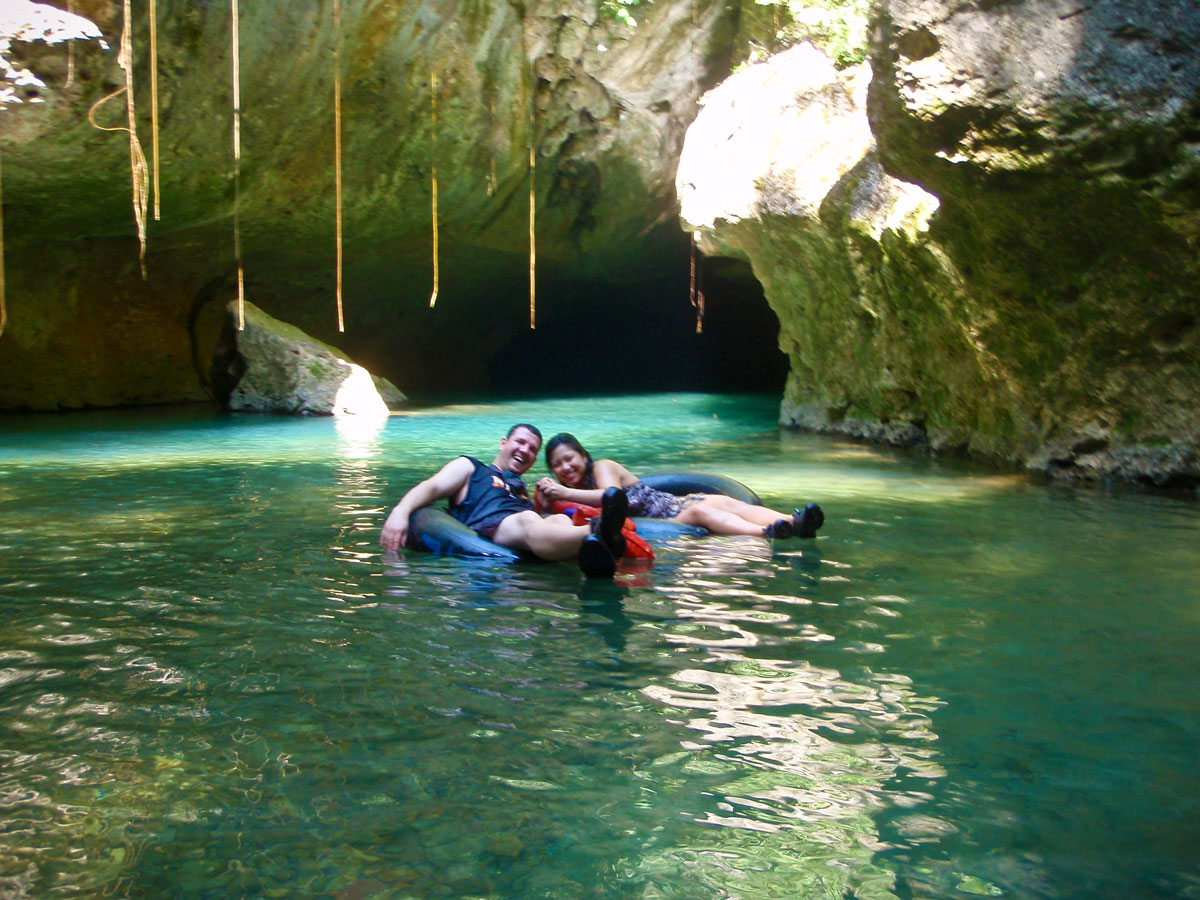 Man and woman cave tubing in Belize's Nohoch Che’en Caves Branch Reserve which is one of the must do activities in Belize.