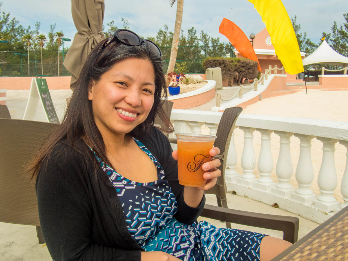 A young asian woman sips a drink at a beach bar in Horseshoe Bay Beach, Bermuda