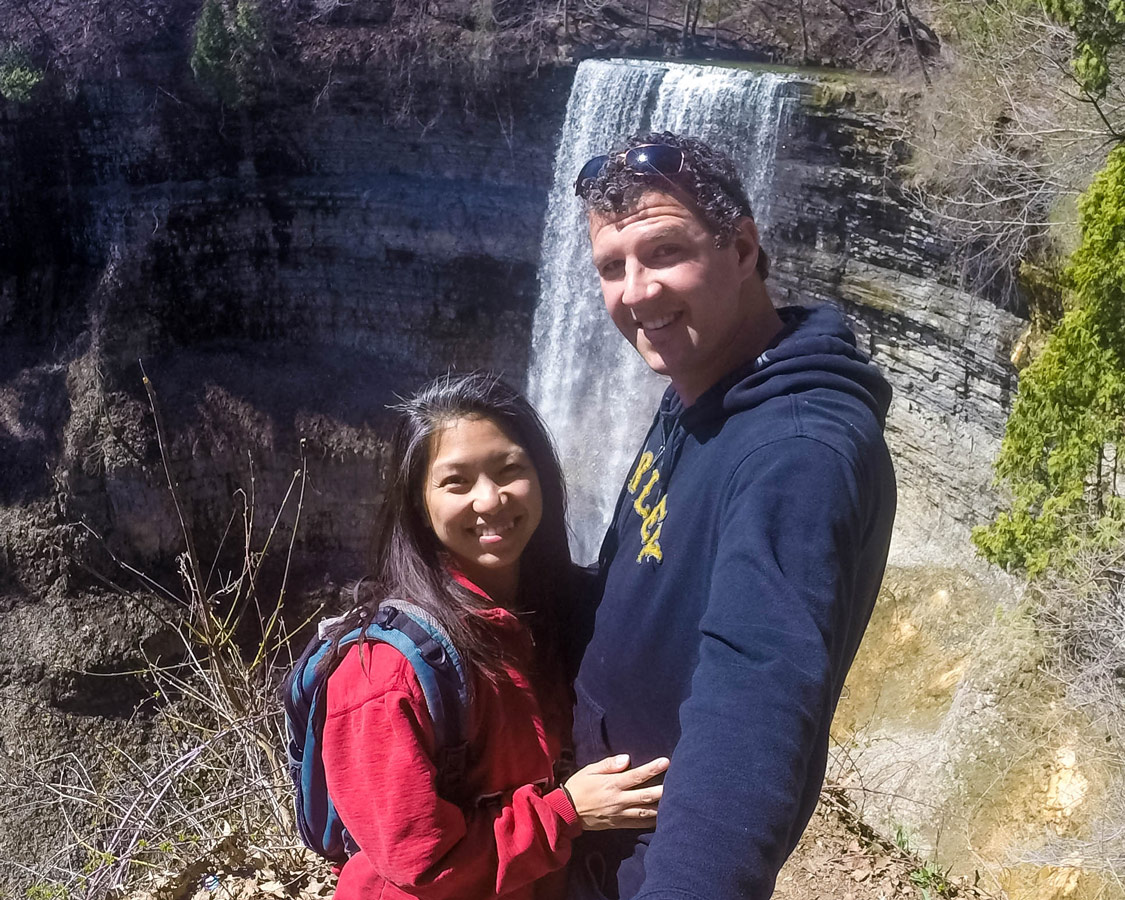 A young couple poses for a selfie in front of a waterfall in Hamilton, Ontario