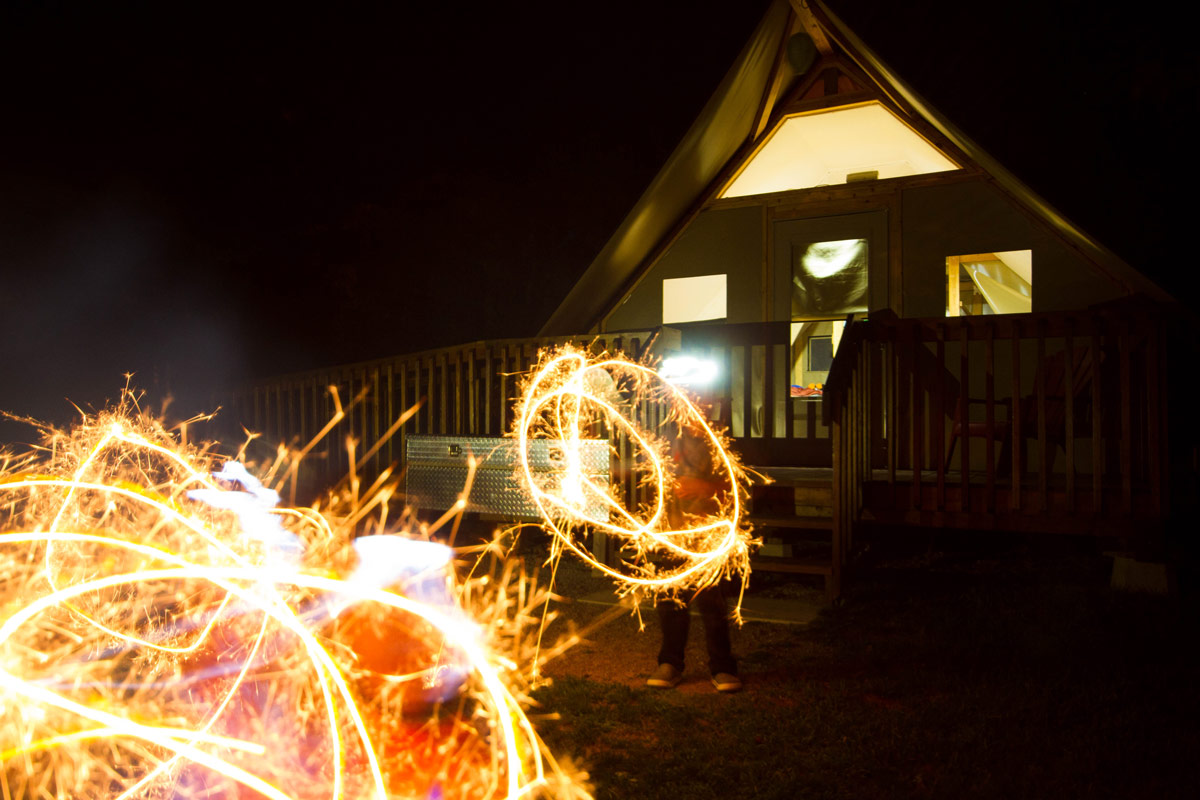 two young boys make sparkler circles in front of a cabin at night in Thousand Islands National Park