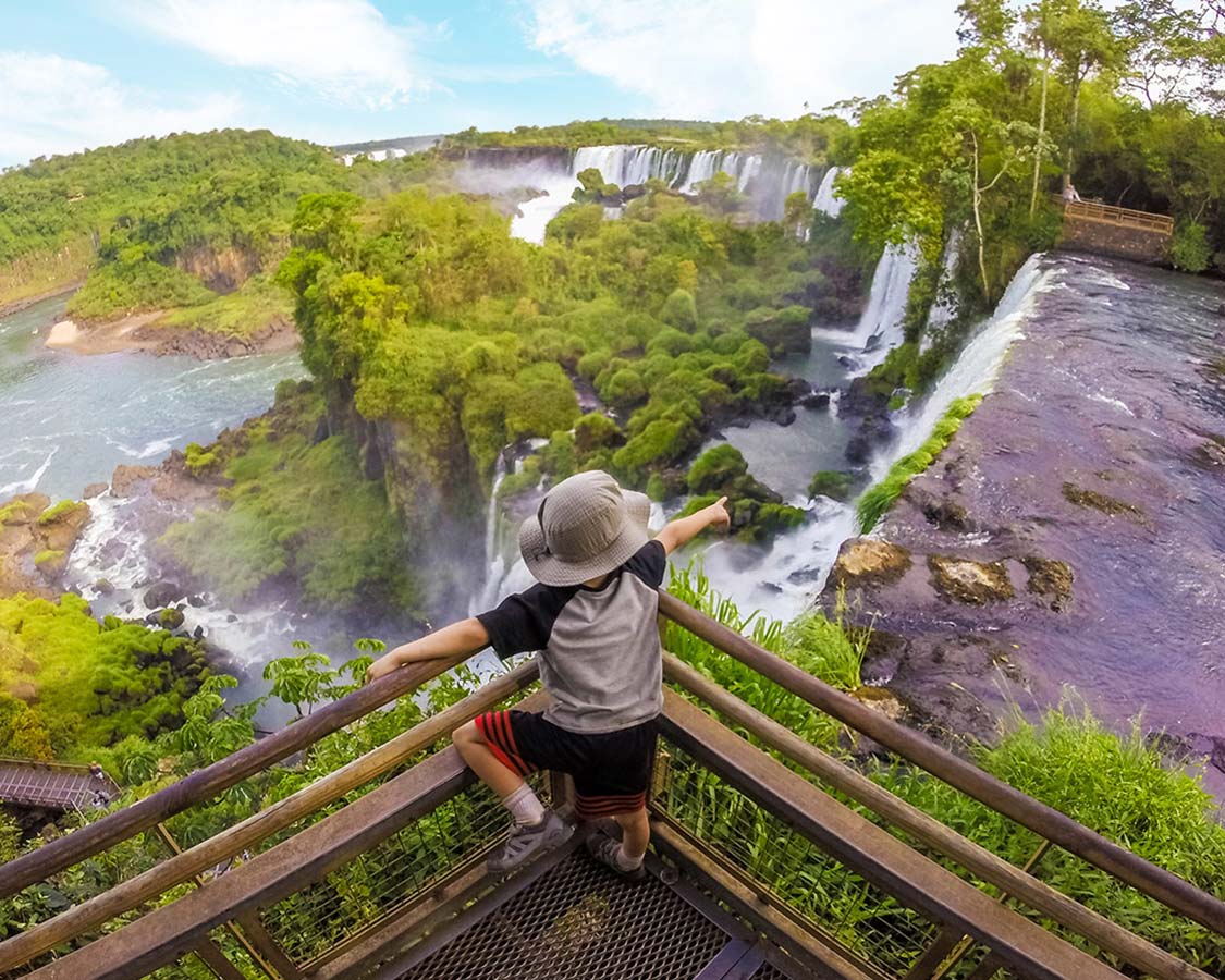 Boy pointing at Iguazu Falls Argentina from boardwalk