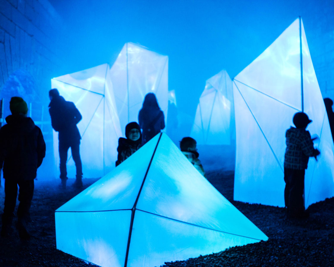 People looking at an Iceberg art installation a great place for exploring when visiting Lumina Borealis with kids in Fort Henry during Lumina Borealis Kingston