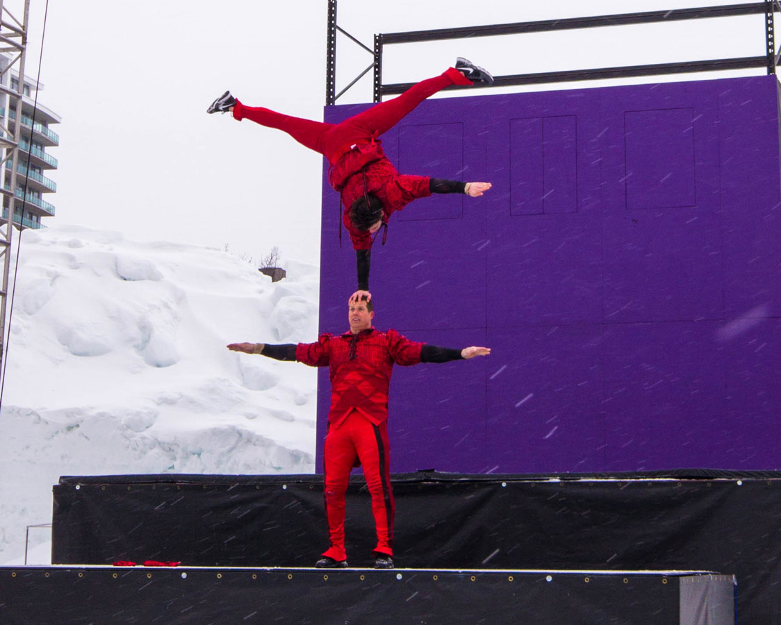 An acrobat balances himself on the head of another acrobat.