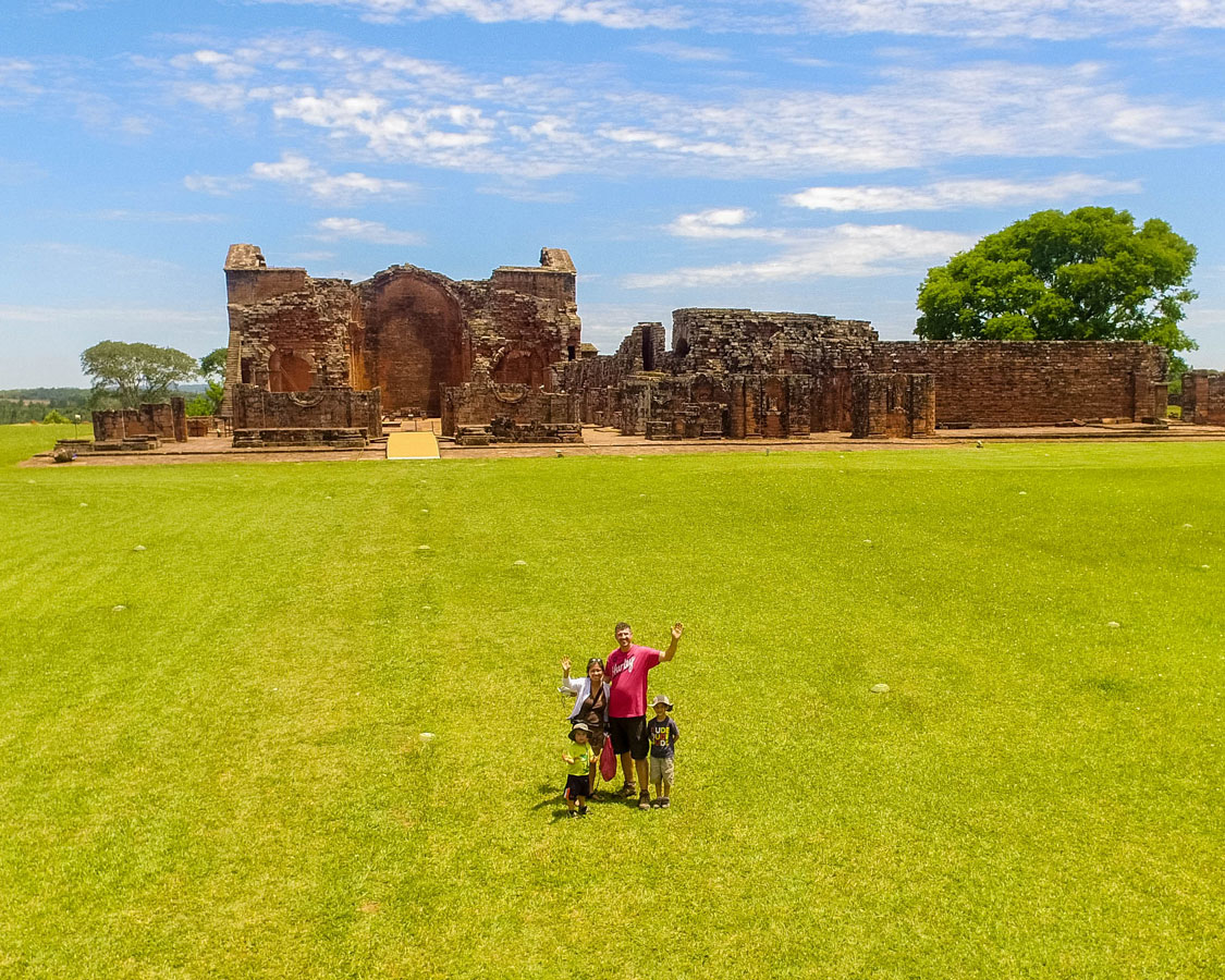 A young family waves to a drone taking the photo in the Jesuit ruins in Paraguay
