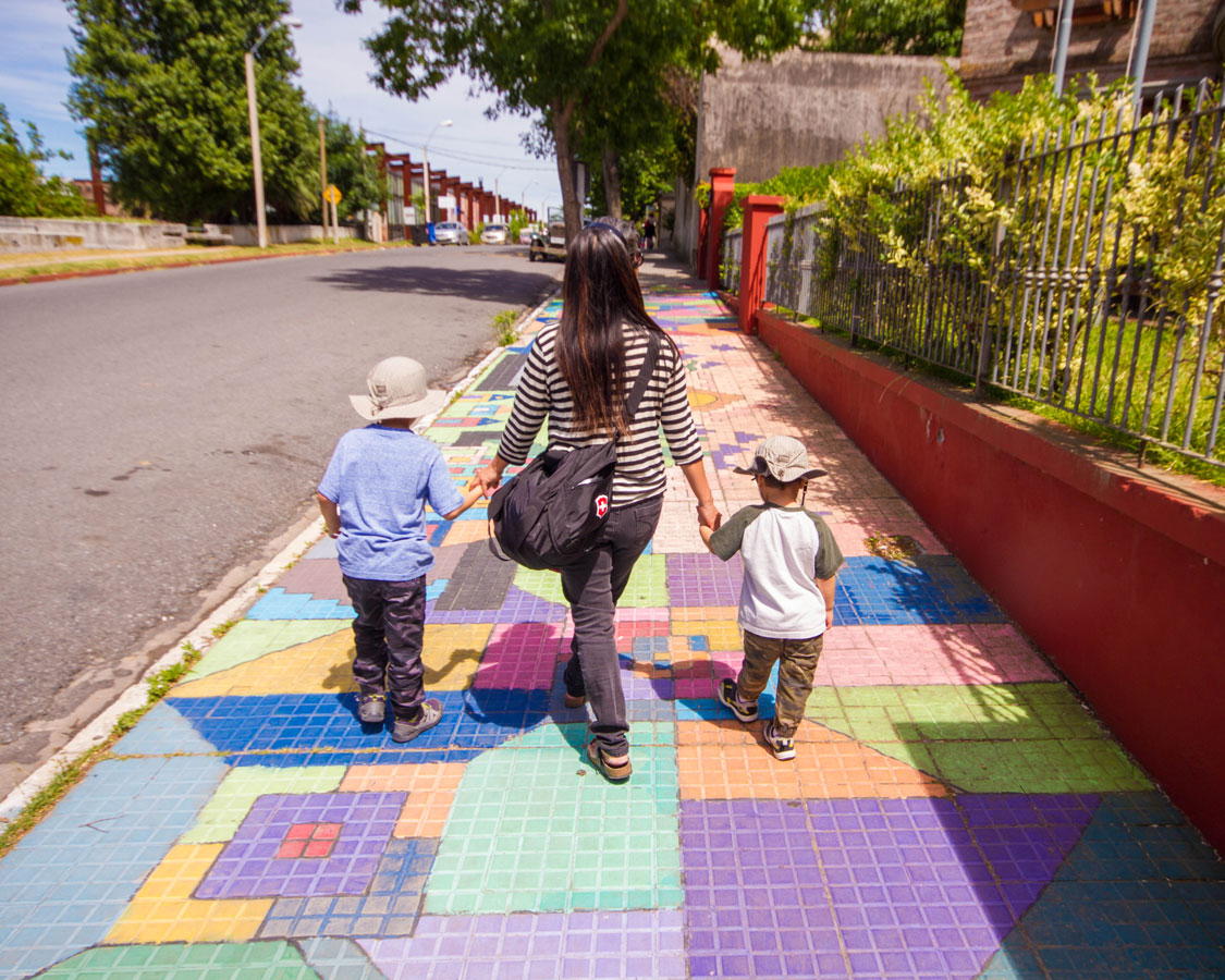 Lady with two kids on either side walk hand in hand on a street in Colonia del Sacramento on the way to Barrio Historico.