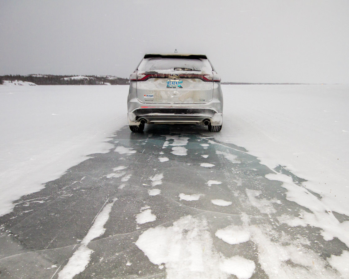 Car driving on Dettah ice road in one of our top winter activities to do in Yellowknife with kids.