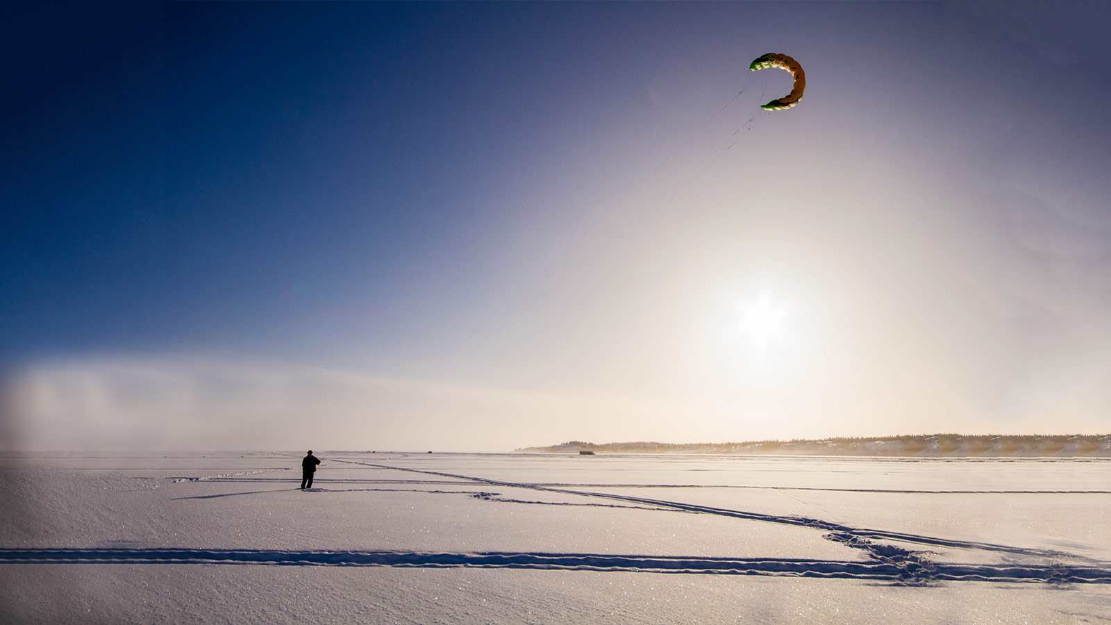 Man kite flying in winter on Great Slave Lake, Yellowknife.