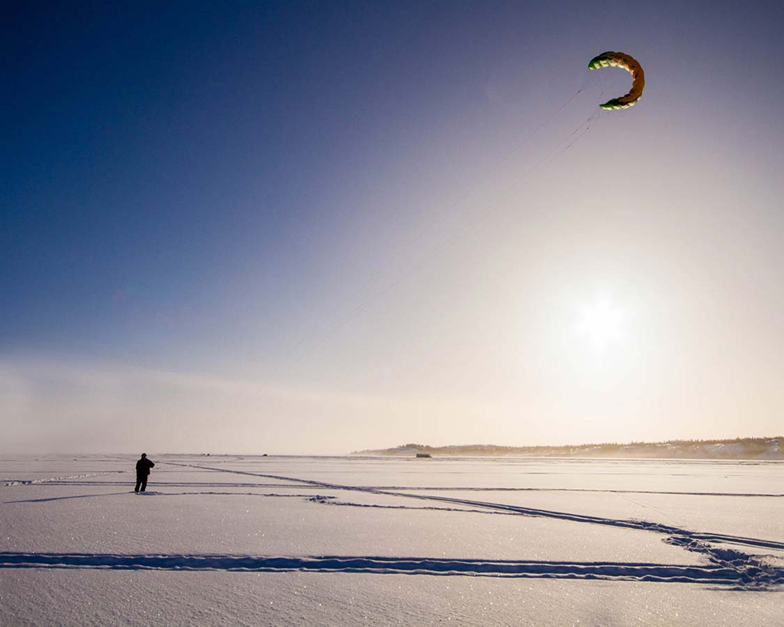 Man kite flying in winter on Great Slave Lake, Yellowknife.