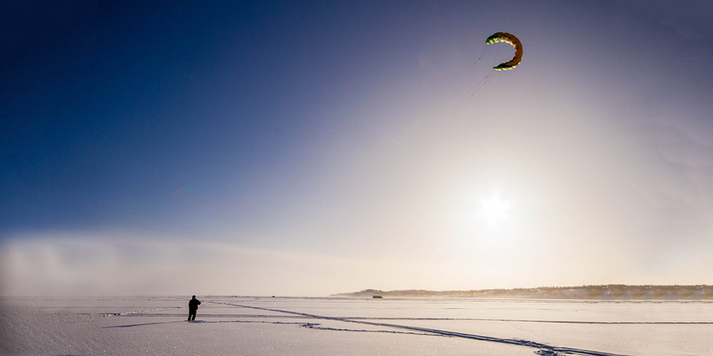 Man kite flying in winter on Great Slave Lake, Yellowknife.