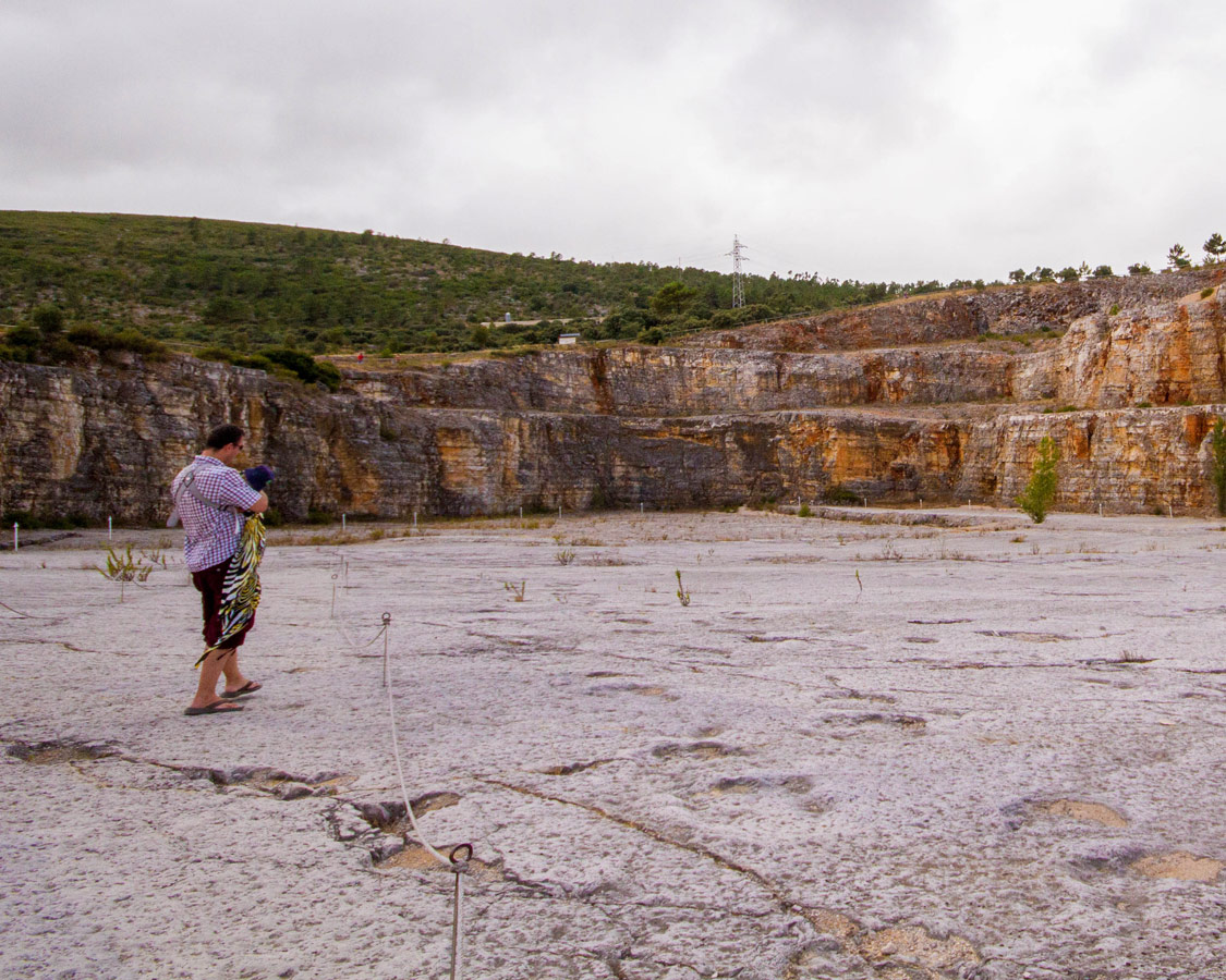 a man carrying a baby through a quarry filled with fossilised dinosaur footprints as a day trip from Fatima, Ourem and Obidos