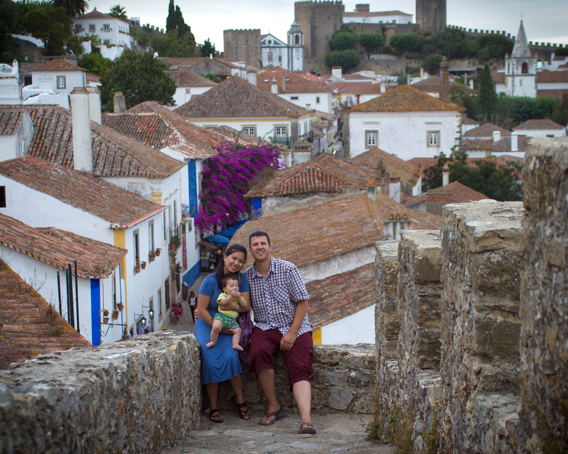 A family takes a photo overlooking the walled city of Obidos, Portugal