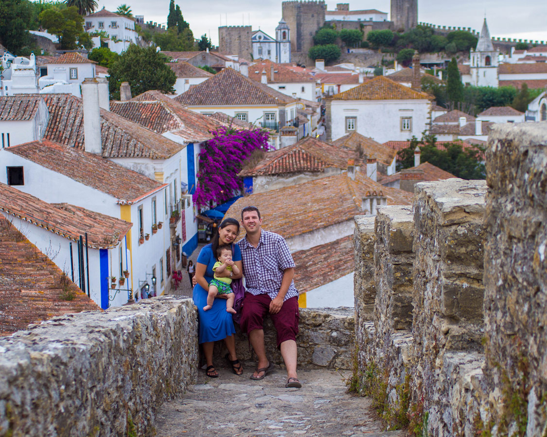 A family takes a photo overlooking the walled city of Obidos, Portugal