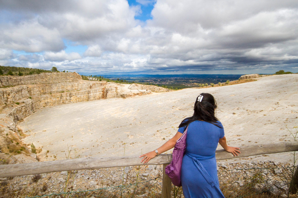 A young womanan looks over a quarry in Portugal that is filled with dinosaur footprints