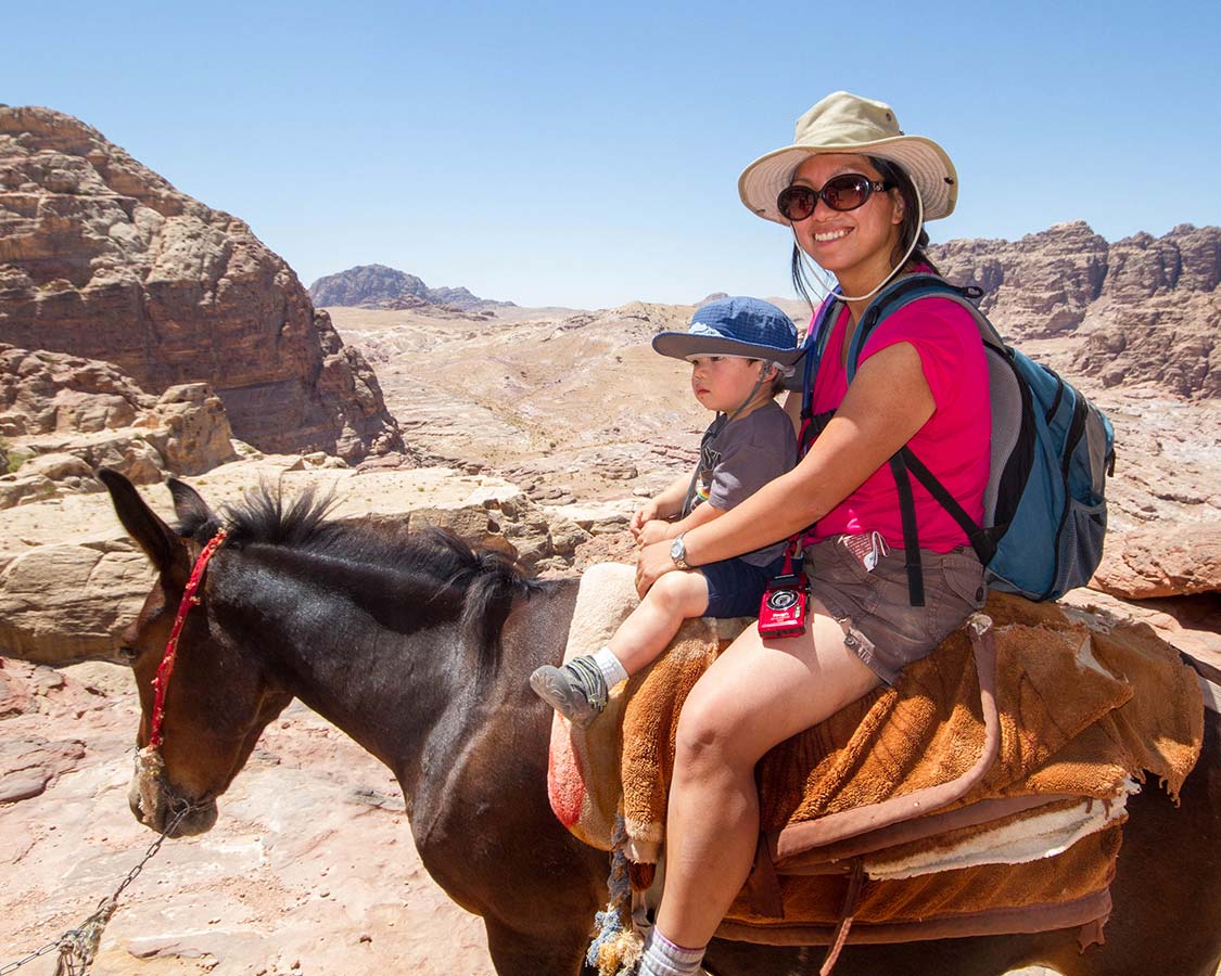 Christina Wagar rides a donkey in Petra with her son