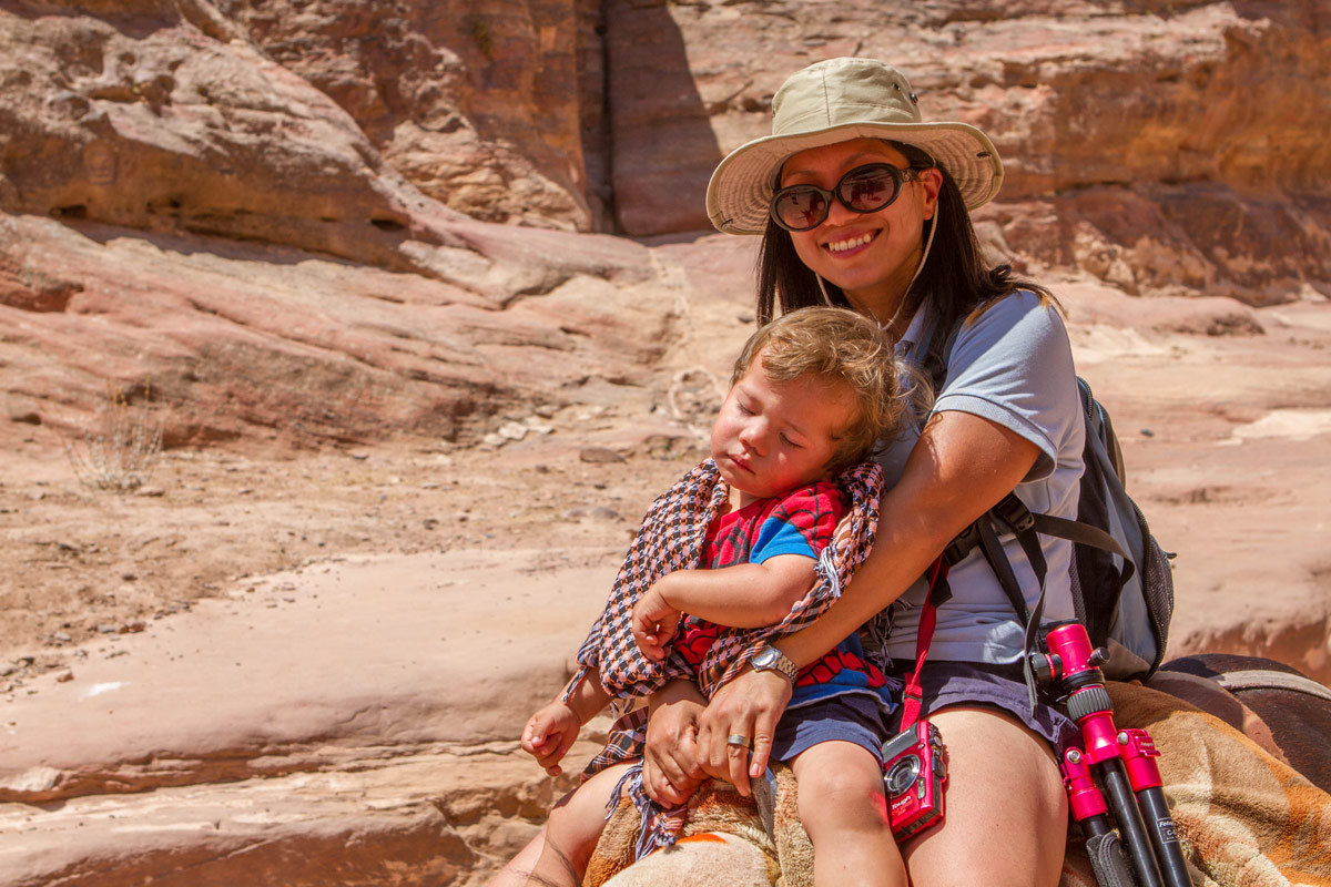 A young boy sleeps on horseback in the arms of his mother on the way down from the Petra Monastery in Jordan