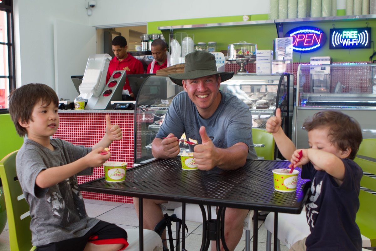 Man with two boys sitting down and having frozen yogurt in St George Bermuda.