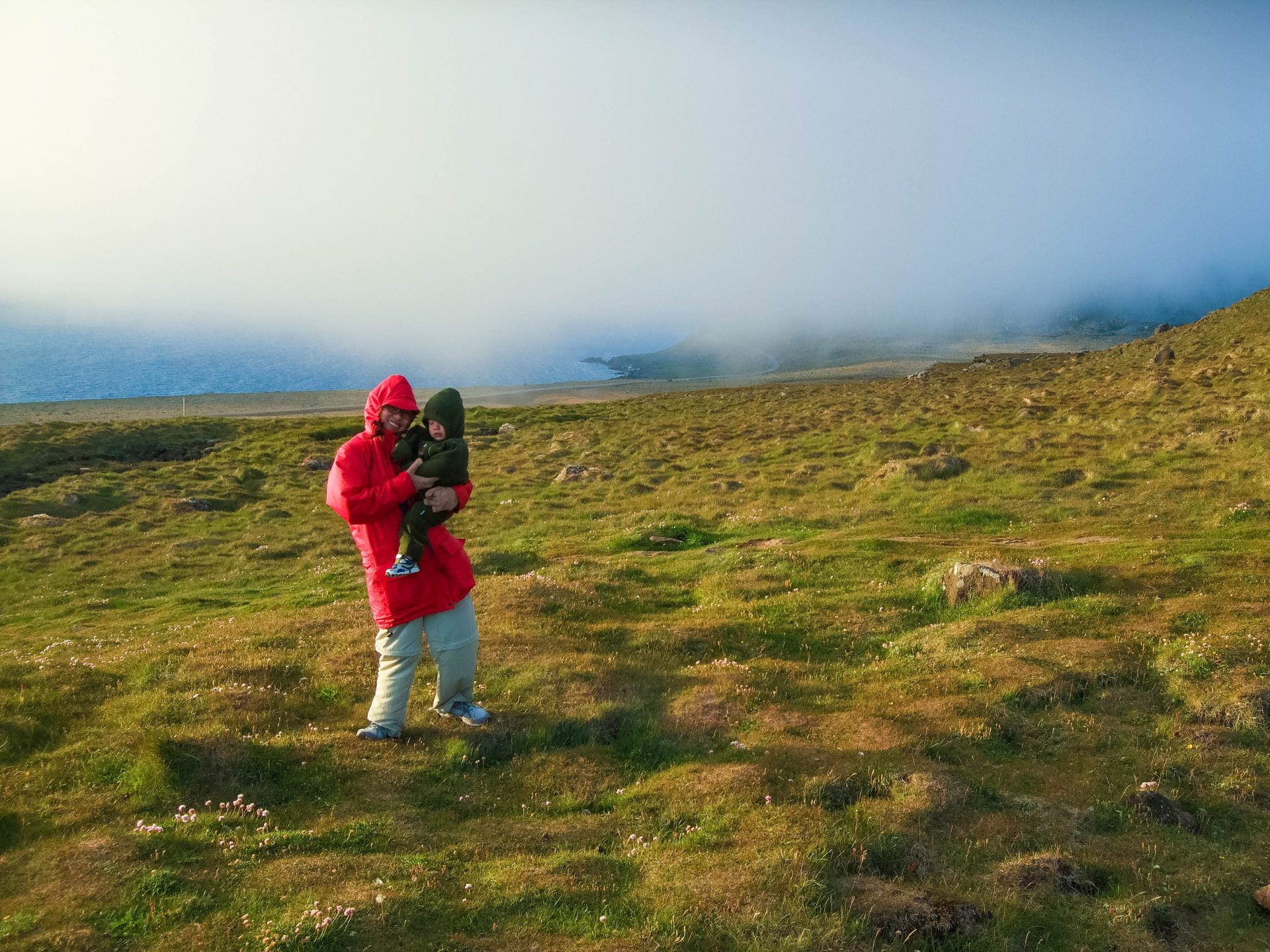 A mother and son brace against the wind as they experience one of the family friendly hikes in Iceland along the Latrabjarg Bird Cliffs in Icelands Westfjords