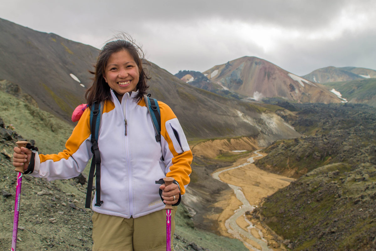 A smiling asian woman hikes through Landmannalaugar in Iceland