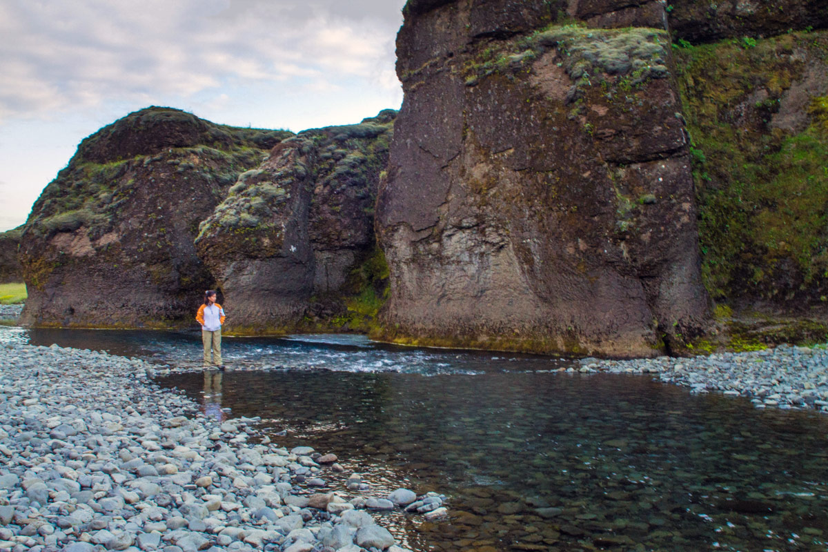 A woman wades through a river in Fjadrargljufur canyon in Iceland