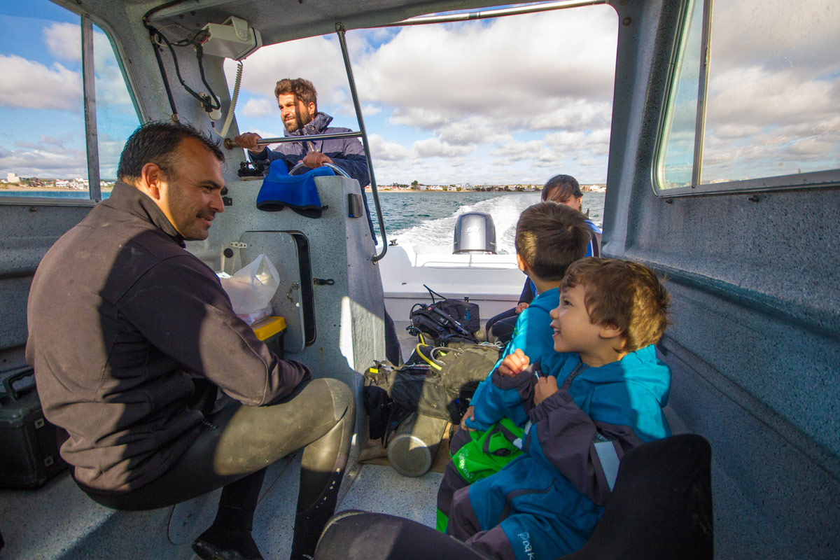 Two young boys chat with a dive master on a small boat in Argentina