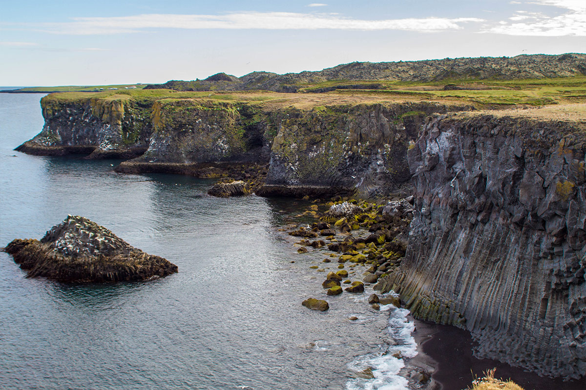 Tall basalt cliffs topped with bright green grass rising from the atlantic ocean make Hellnar a great family friendly hike in iceland