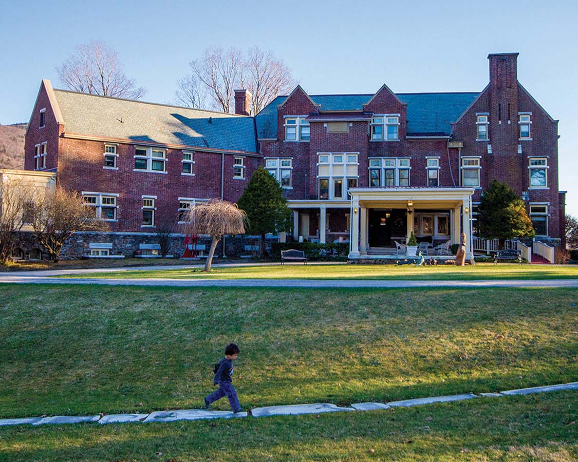 Boy walking on a path in front of The Wilburton Inn which is located on the 30-acre Wilburton Estate in Manchester, Vermont.