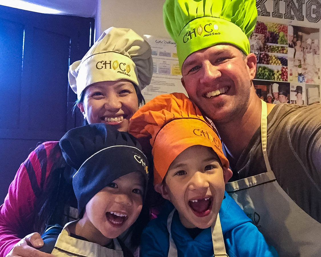 A young interracial family wearing colorful chef hats smiles during the ChocoMuseo in Cusco Peru