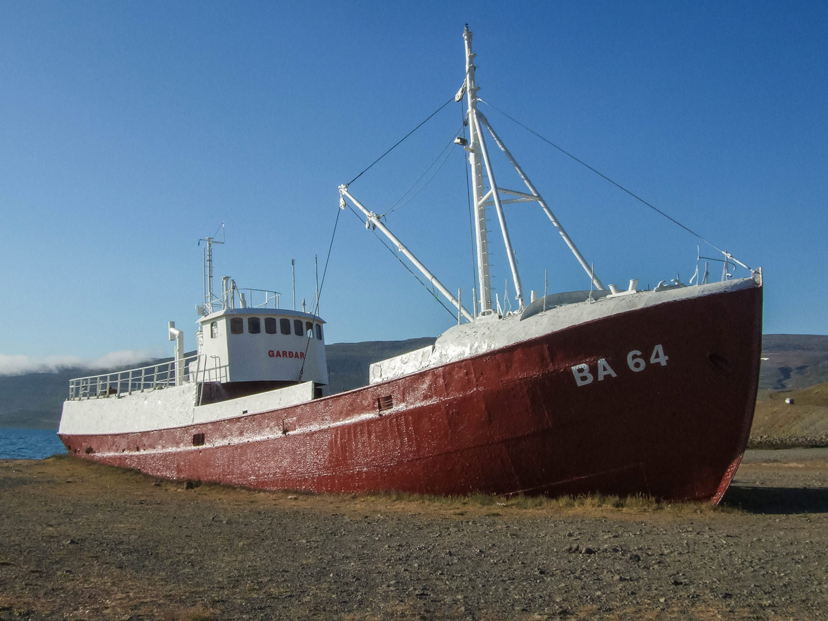 The Icelandic steelship Gardar, a red and white fishing boat, beached along the shores of Iceland's Westfjords