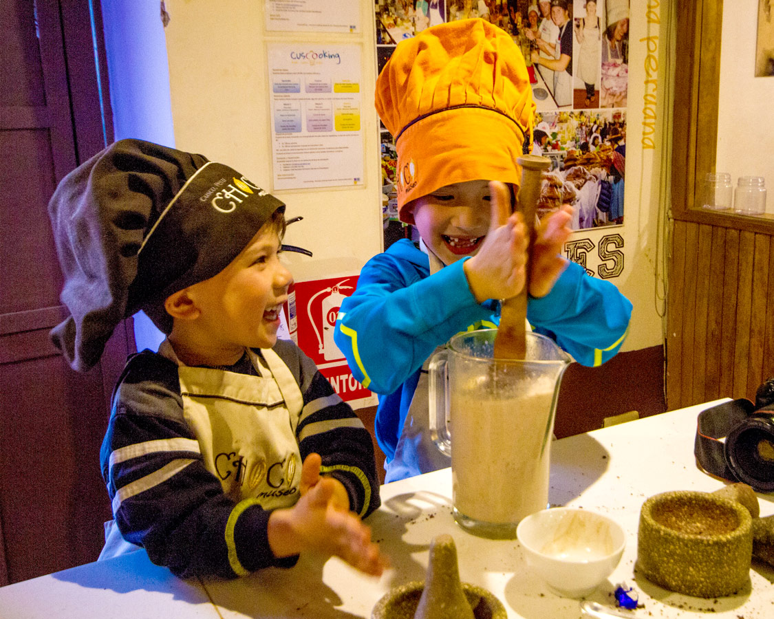 Two young boys stir a jug of homemade hot chocolate at the Cusco ChocoMuseo in Peru