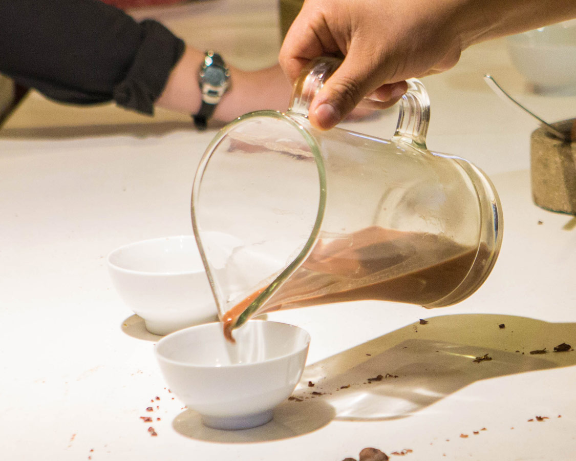 A hand pours chocolate tea into a bowl at the ChocoMuseo in Cusco Peru