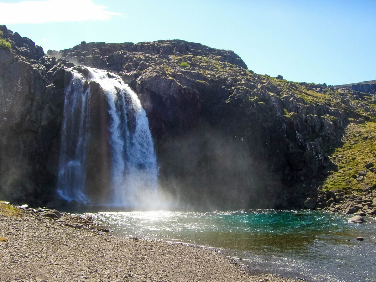 A small waterfall pours over a cliff along the highway in Iceland's westfjords