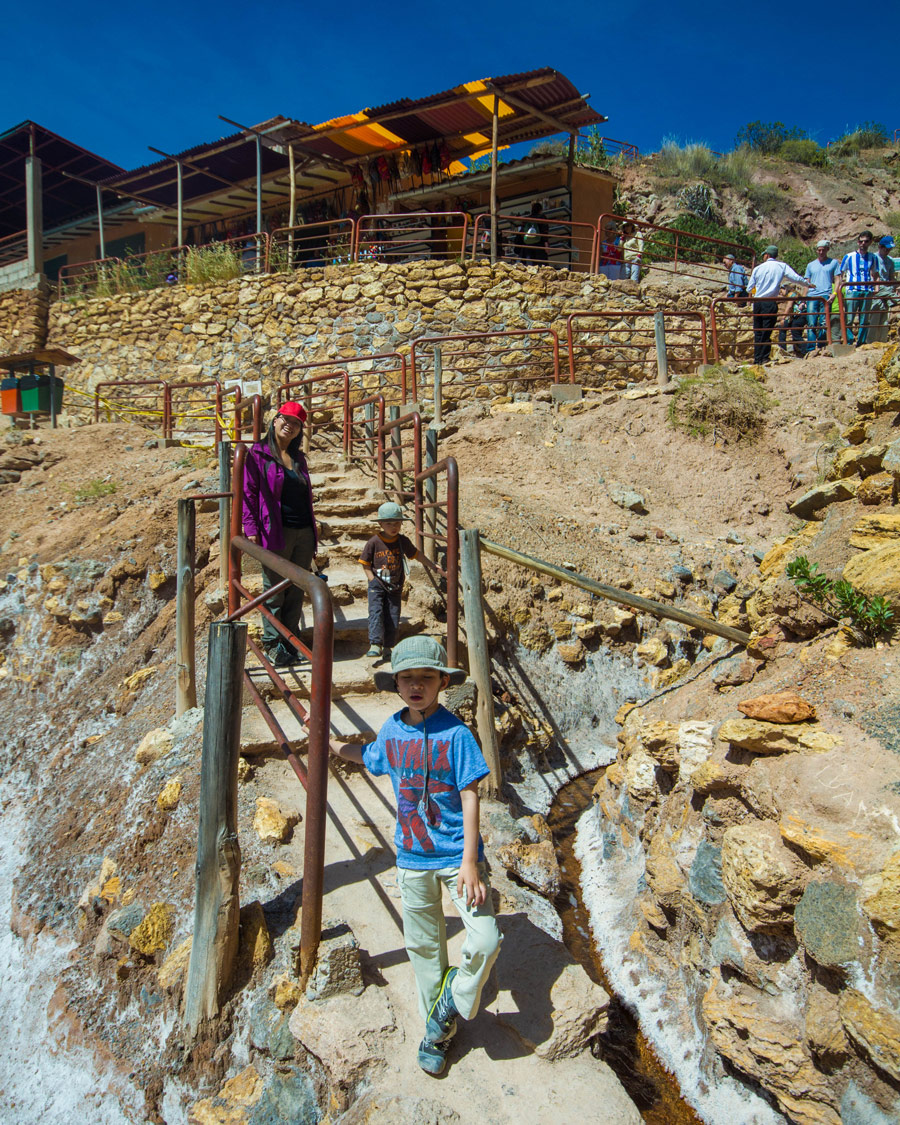 Family walking down the stairs towards the salt pans of Maras Peru