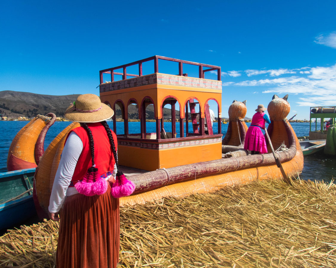 An Uros woman prepares to board a balsa reed boat on Lake Titicaca Peru. They can use these boats to transport families visiting Lake Titicaca with kids