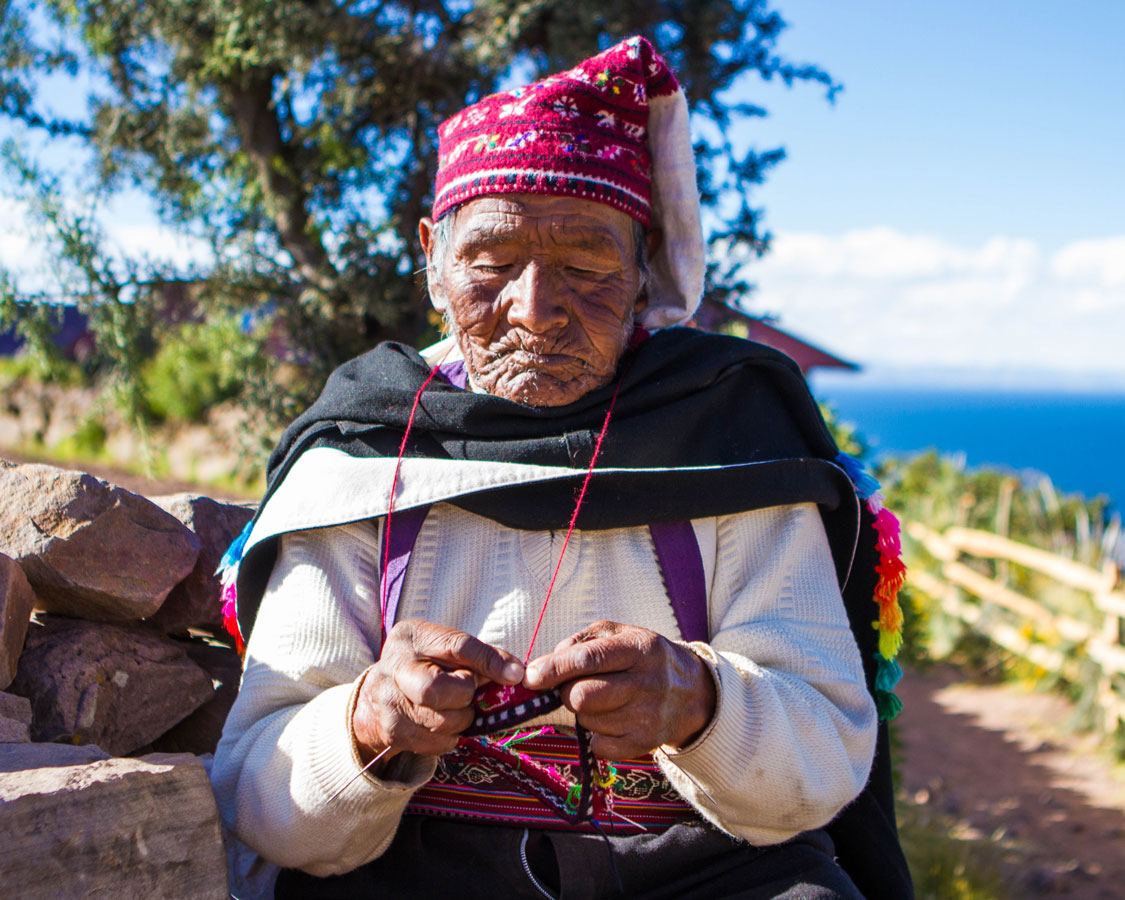 An elderly Taquileno man knits a hat on Isla Taquile on Lake Titicaca Peru