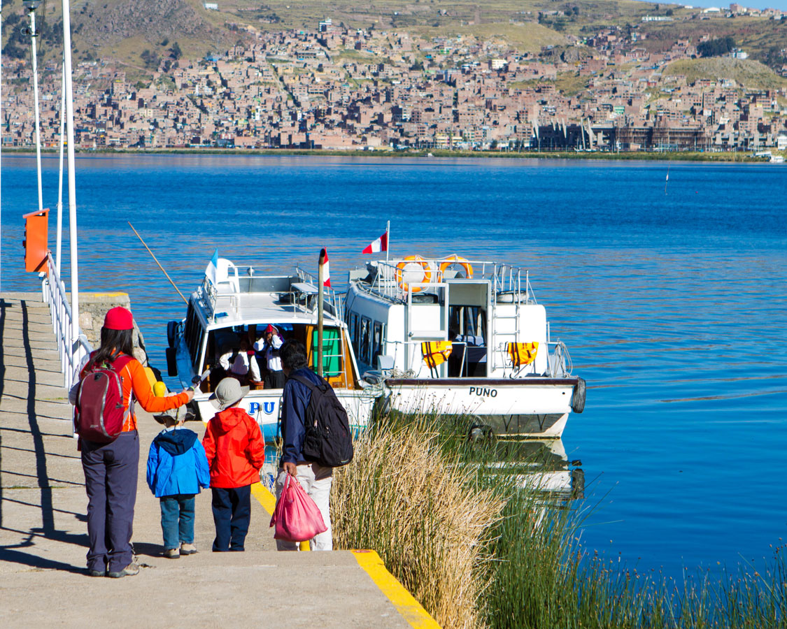 A family boards a tour boat at the Libertador Marina in Puno, Peru as they prepare to visit Lake Titicaca with kids