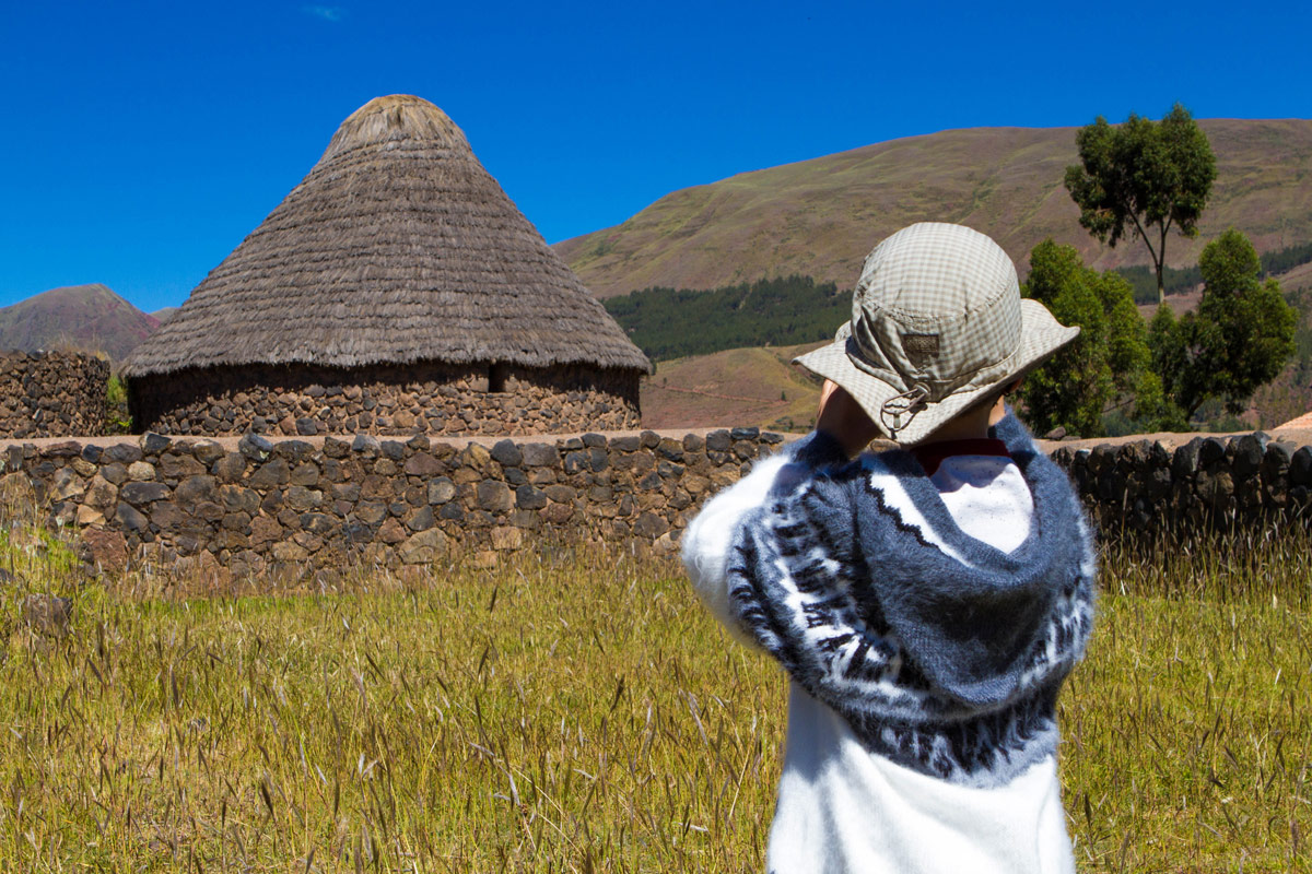 A young boy takes a photograph of inca silos in Raqchi Peru during the Cusco to Puno bus tour in Peru