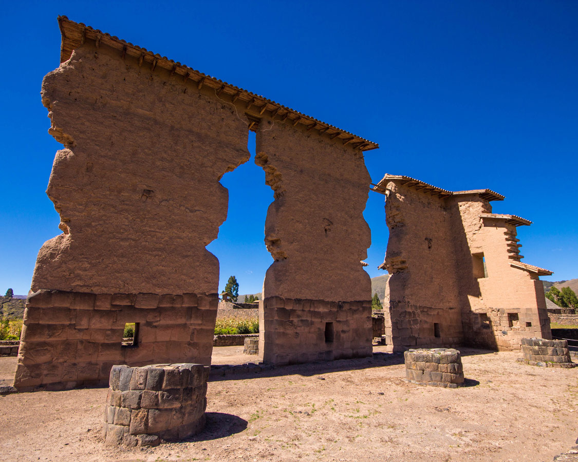 The towering 14 meter high Inca ruins of Raqchi Peru stand out against the blue sky on a stop on the Cusco to Puno bus
