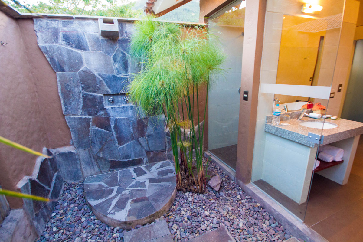An outdoor shower at the Casa Andina Private Collection Sacred Valley Peru features a stone wall and surrounding plants