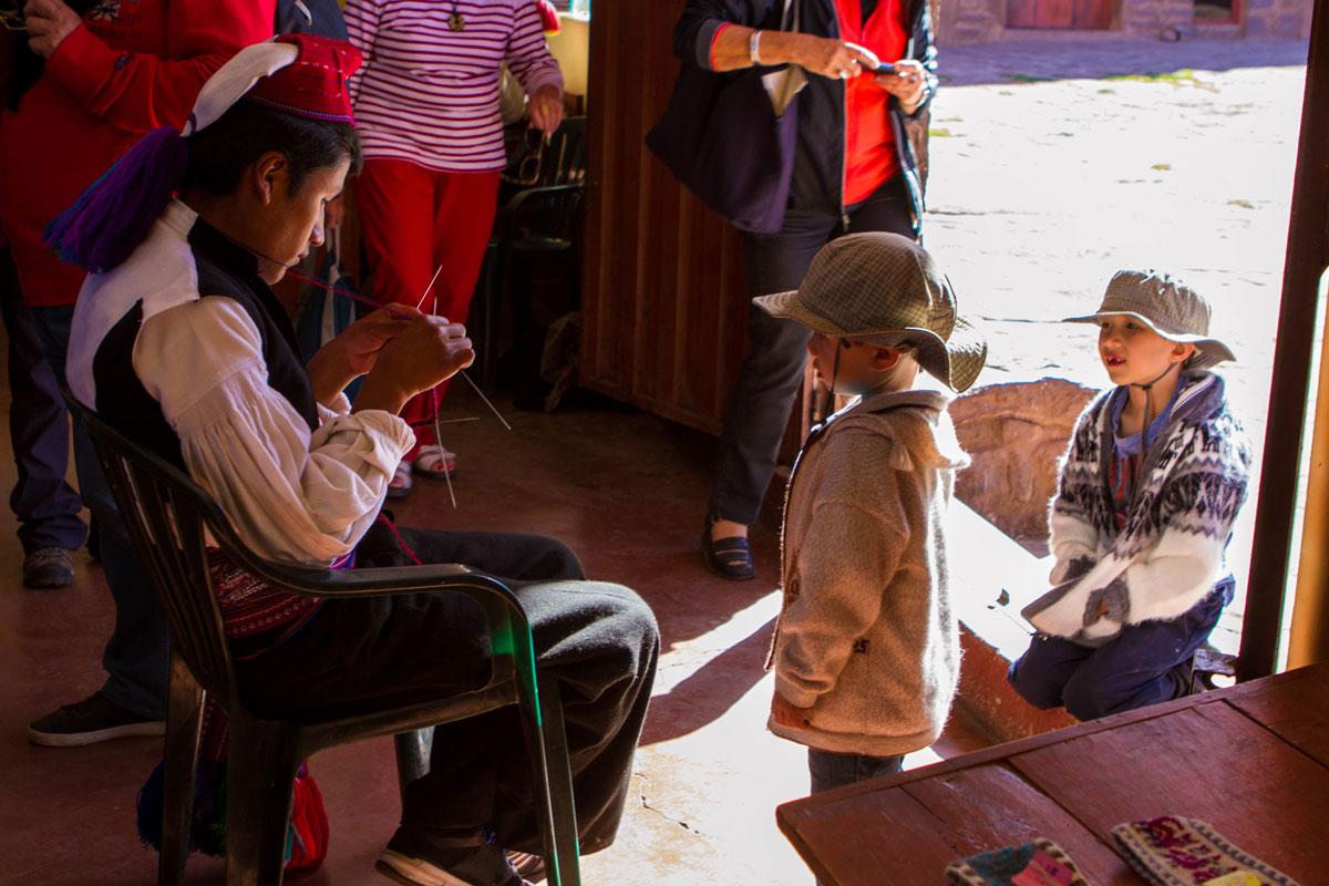While visiting Lake Titicaca with kids we came across a young Taquileano man in traditional clothing knitting inside the handicraft store on Isla Taquile