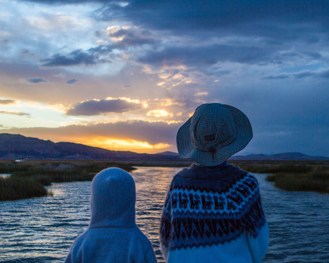 Two boys watching the sunset over lake Titicaca Peru on a journey to Lake Titicaca with kids