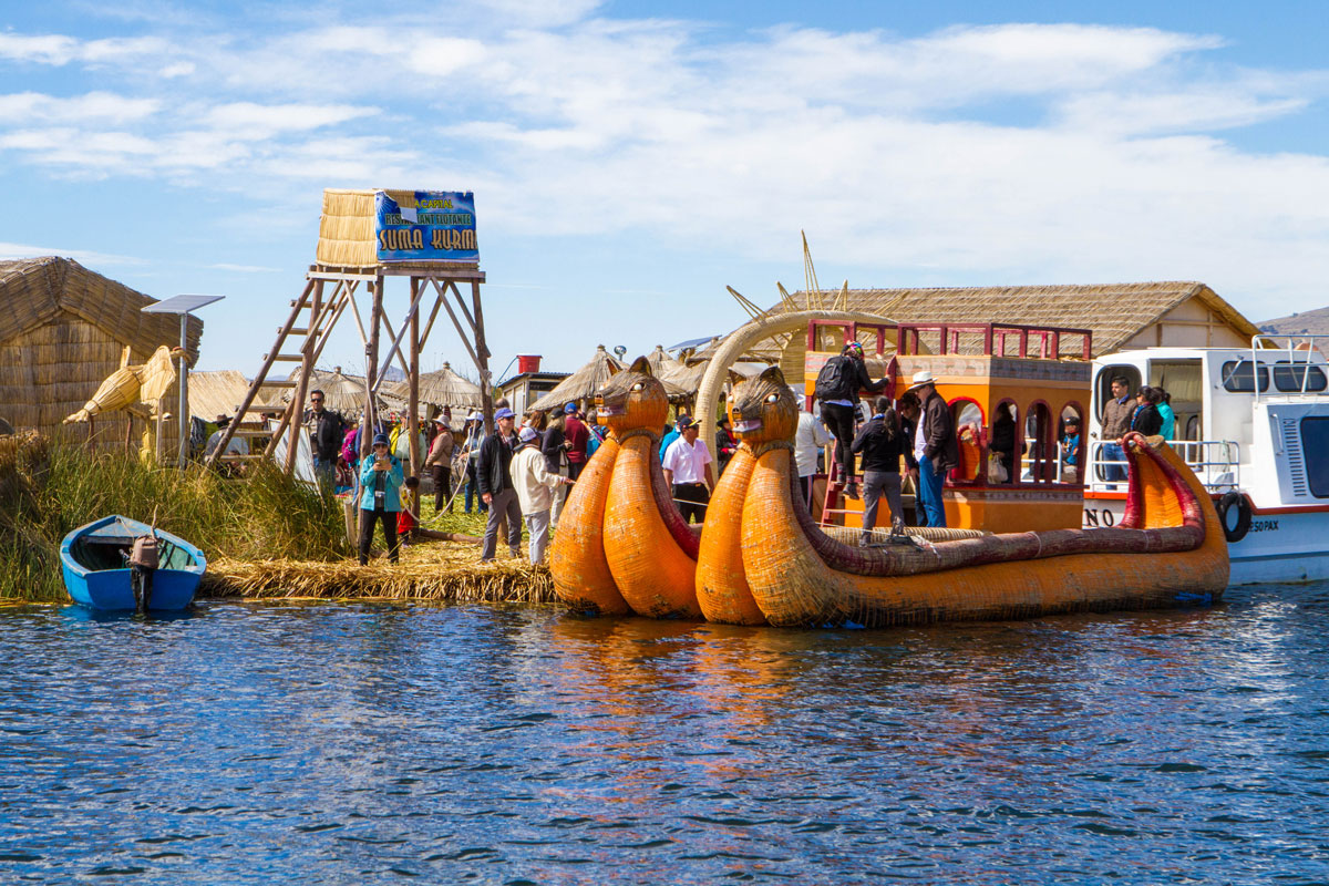 A floating reed island in Lake Titicaca with a reed lookout tower and a colorful balsa boat