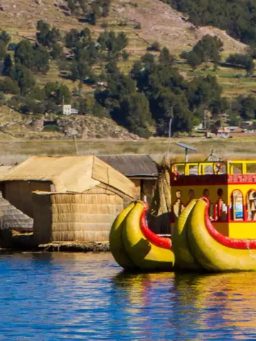 An Uros reed boat floats on the clear blue water of Lake Titicaca, Peru