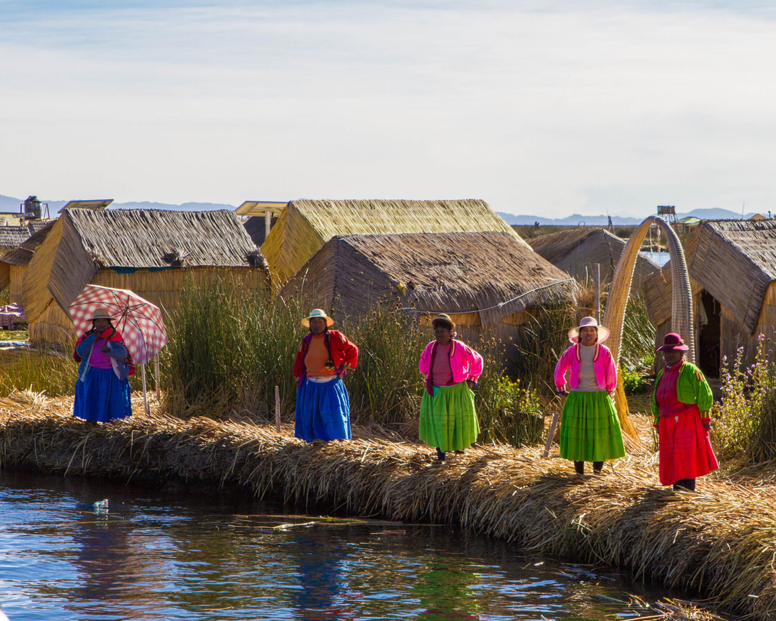 Uros women in traditional clothing prepare to greet visitors to Isla de los Uros on Lake Titicaca Peru