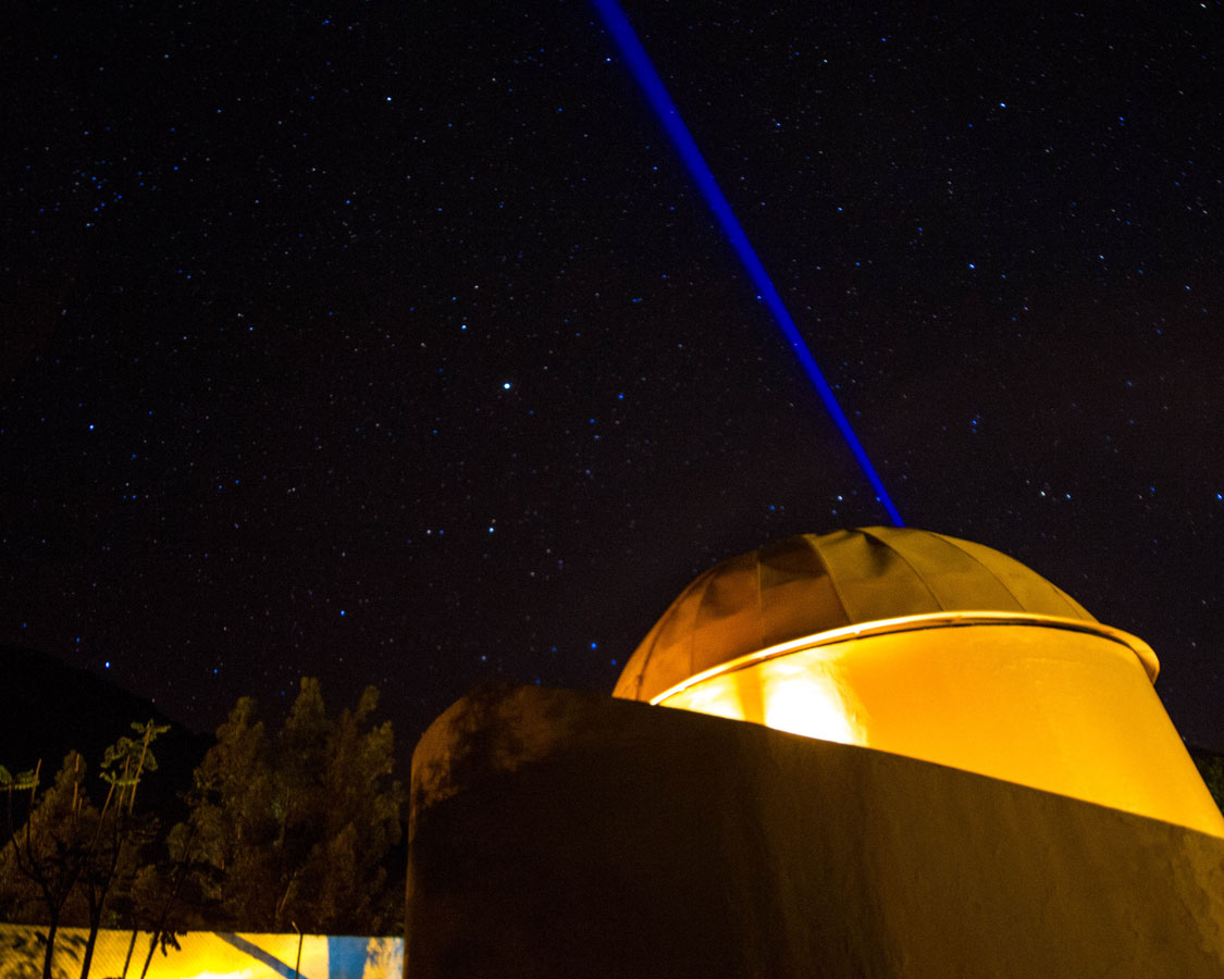 A blue laser shines in the sky of the Planetarium at the Casa Andina Private Collection Sacred Valley Peru