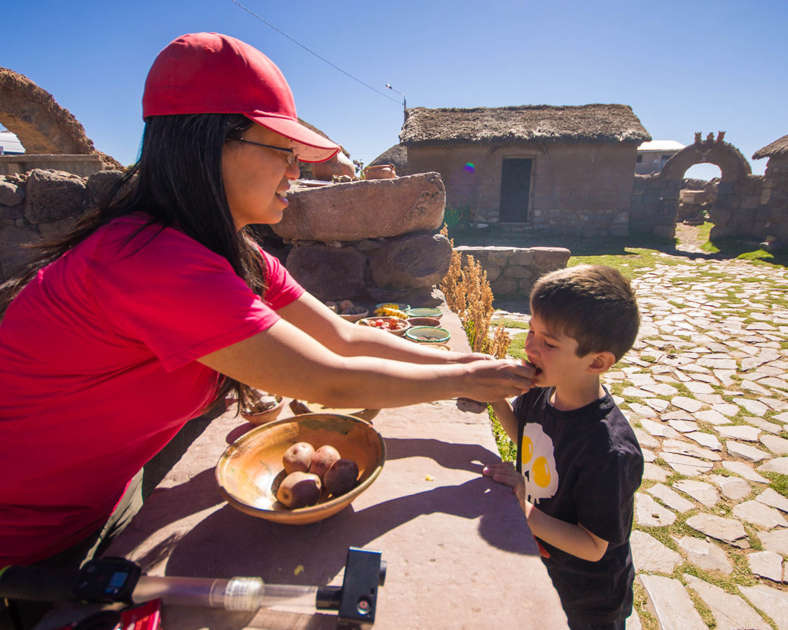 Christina Wagar gives her son a taste of potato and clay, a food said to aid stomach trouble, at a small Peruvian village near Puno on the way to see the Andean Condors in Colca Canyon with kids