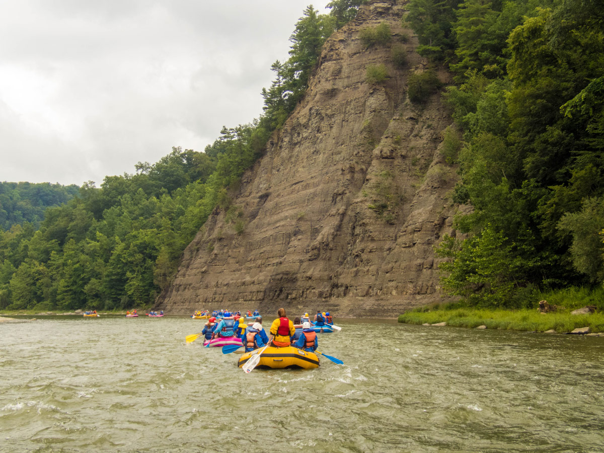 A yellow and a blue raft full of people rafting the river in Letchworth State Park in New York State