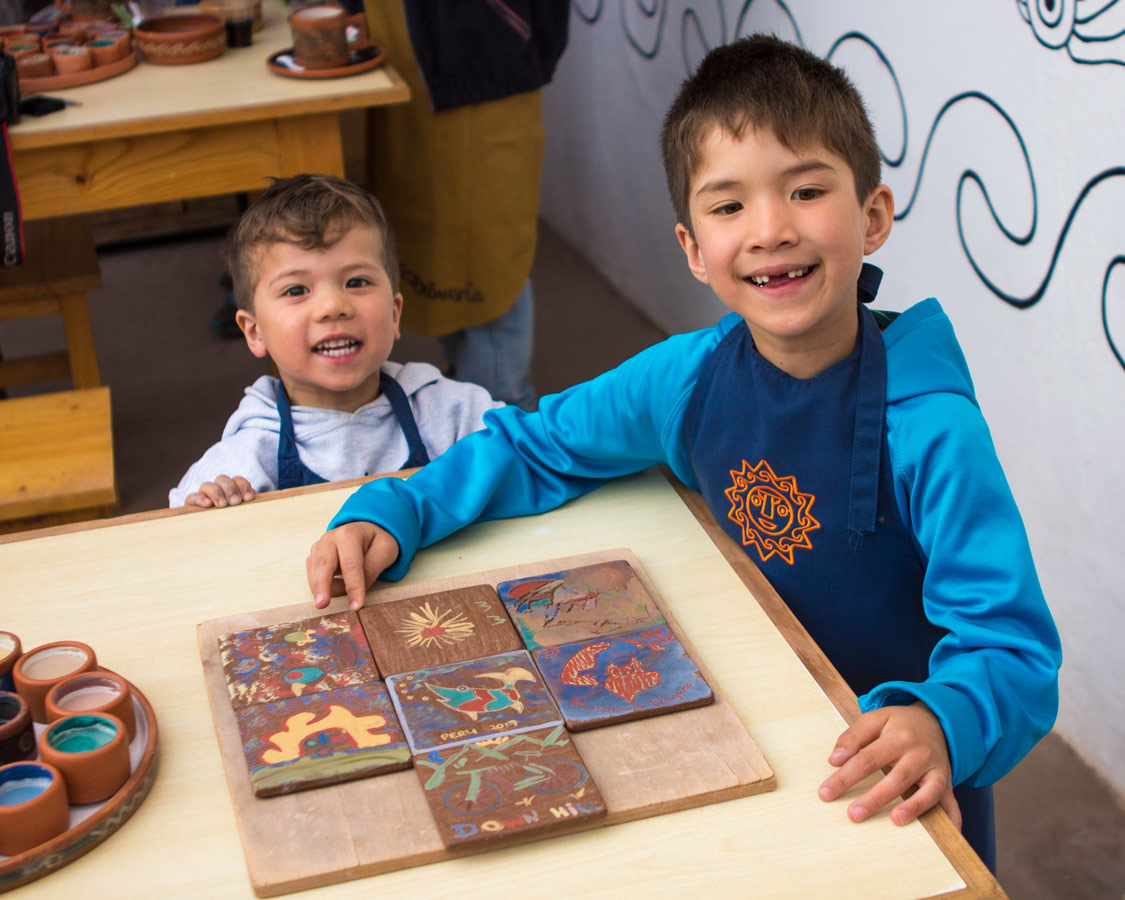 two boys show off their ceramics painting for kids art at the Pablo Seminario Urubamba Peru workshop