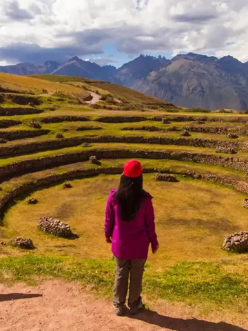 Womn standing on a trail overlooking the Moray terraces in Peru's Sacred Valley