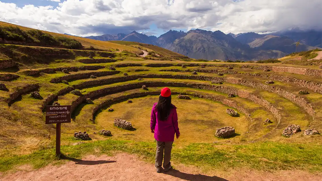 Womn standing on a trail overlooking the Moray terraces in Peru's Sacred Valley