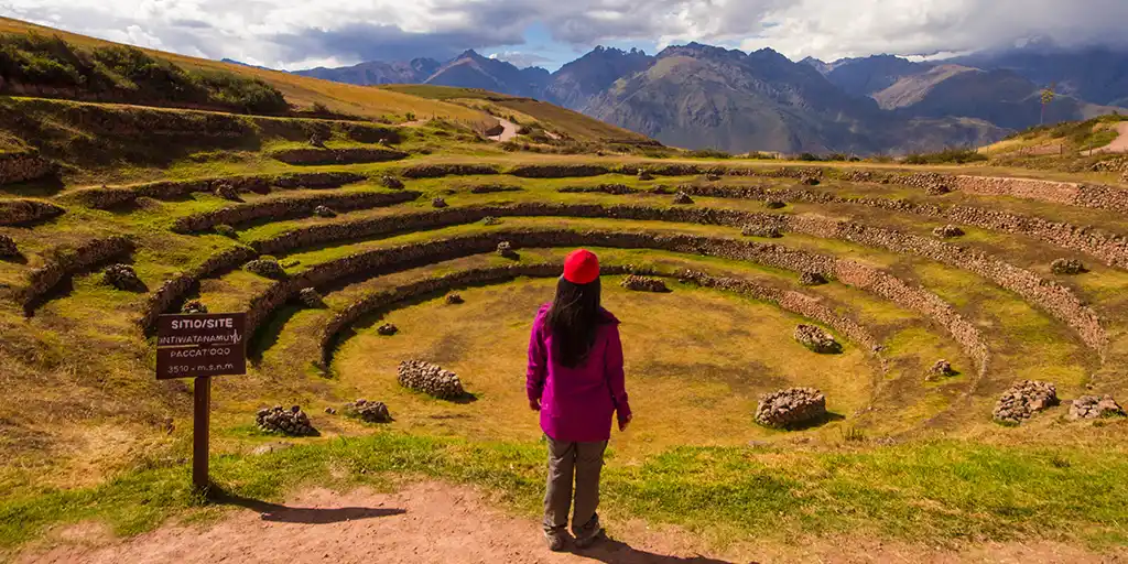 Womn standing on a trail overlooking the Moray terraces in Peru's Sacred Valley